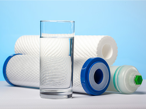 clean glass of water sitting in front of different water filters.