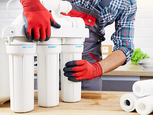 Technician working on a water filtration system, preparing it for installation.