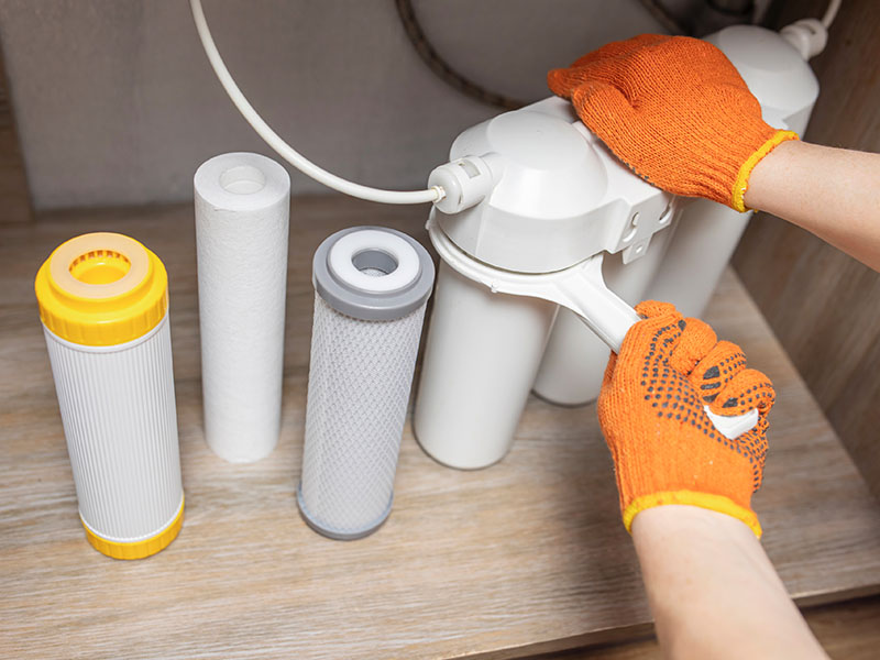 Person opening water filtration canister to replace filter.