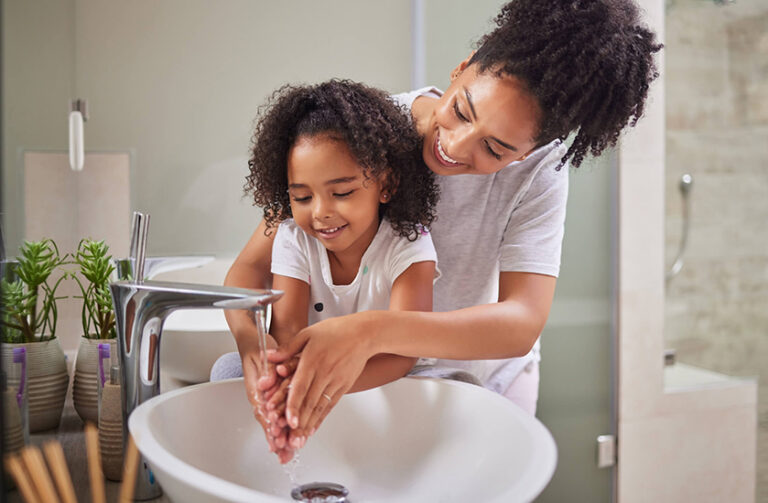 Mom helping daughter wash hands