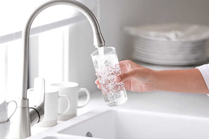 glass of water being filled up from a sink