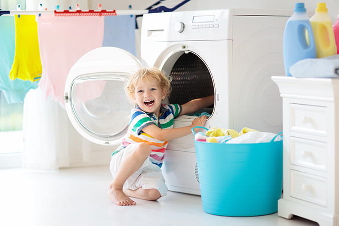 child taking laundry out of a dryer