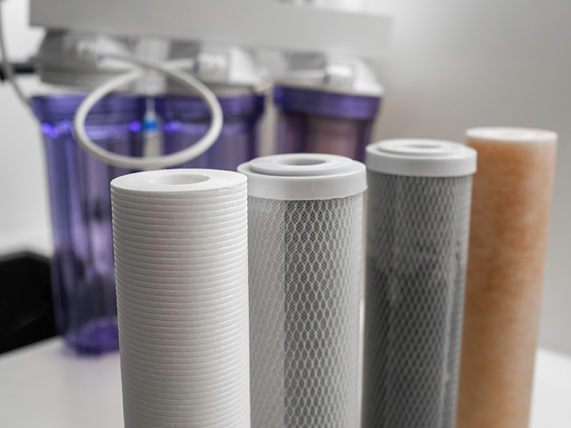 Closeup of water treatment system filters with the system visible in the background.