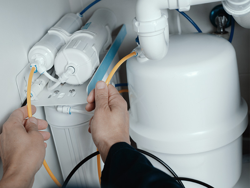 Technician adjusting the connections on an under the sink water filtration system